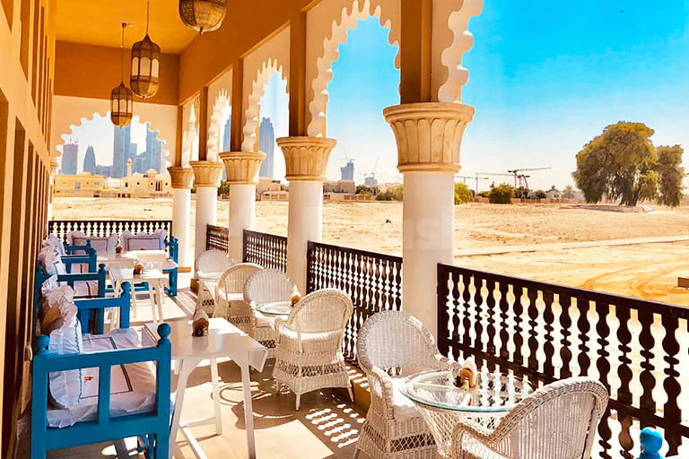 Rooftop terrace at Arabian Tea House Restaurant & Cafe Sharjah featuring ornate stone columns and arched openings overlooking desert