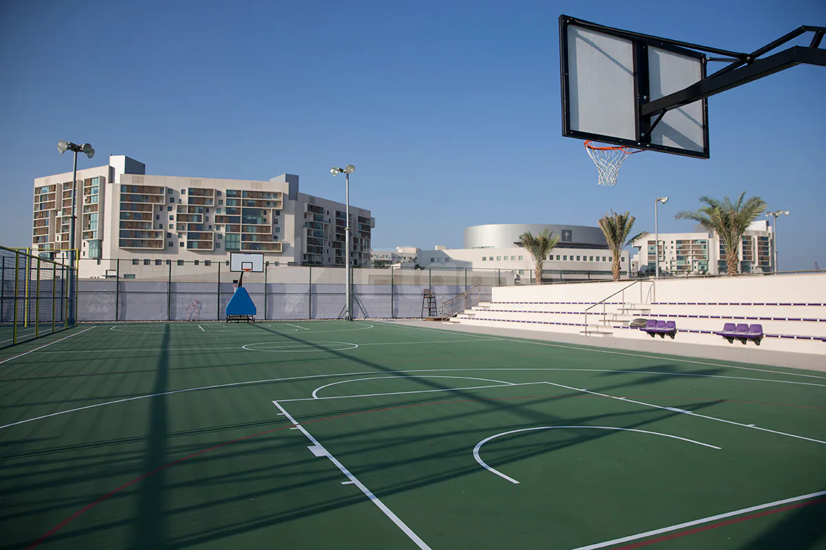 Outdoor basketball court at NYU Abu Dhabi Athletic Field in Abu Dhabi with green synthetic surface, white lines