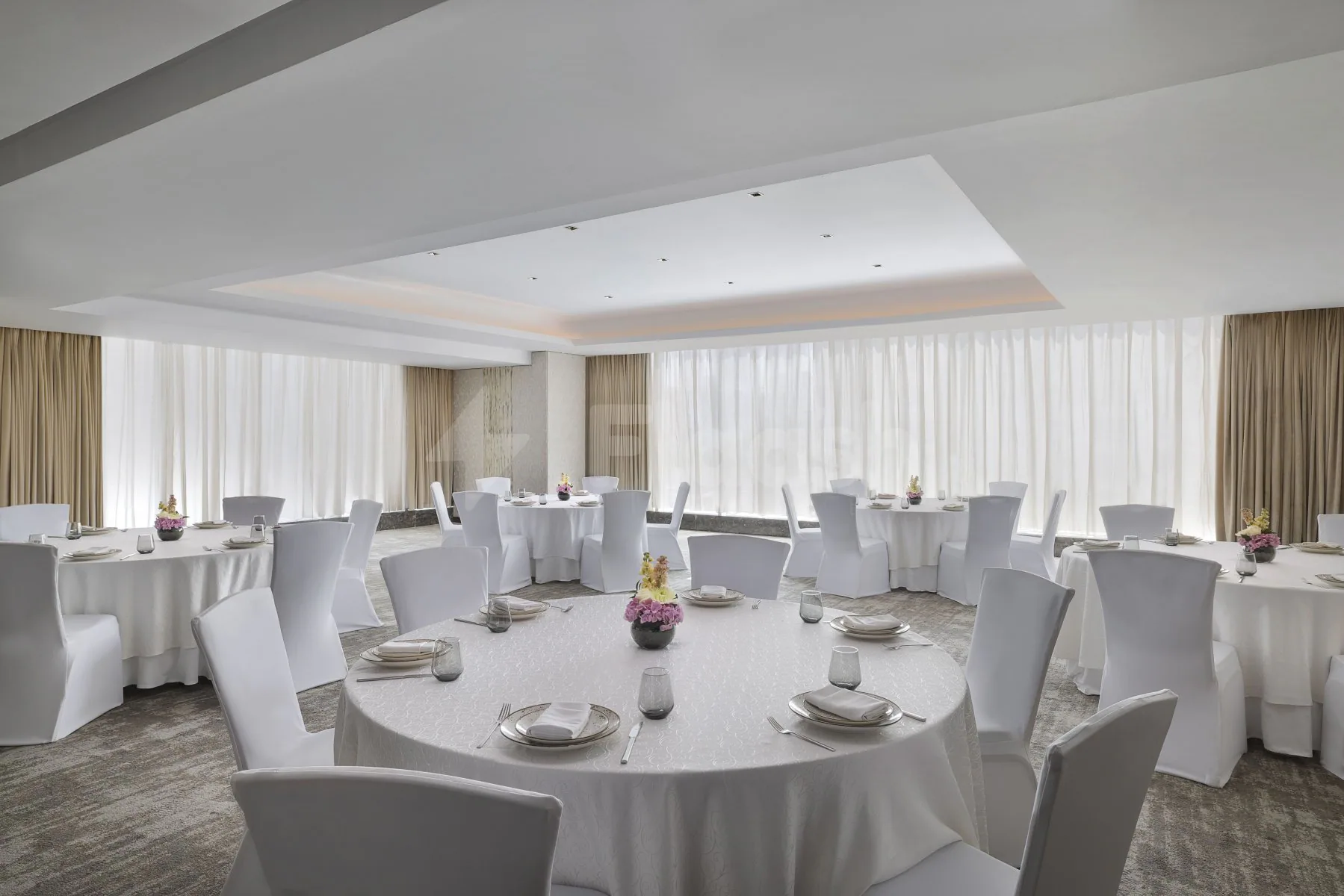 Ballroom at Signature by Sanjeev Kapoor Restaurant Dubai with round tables, white chair covers, floral centerpieces, and large