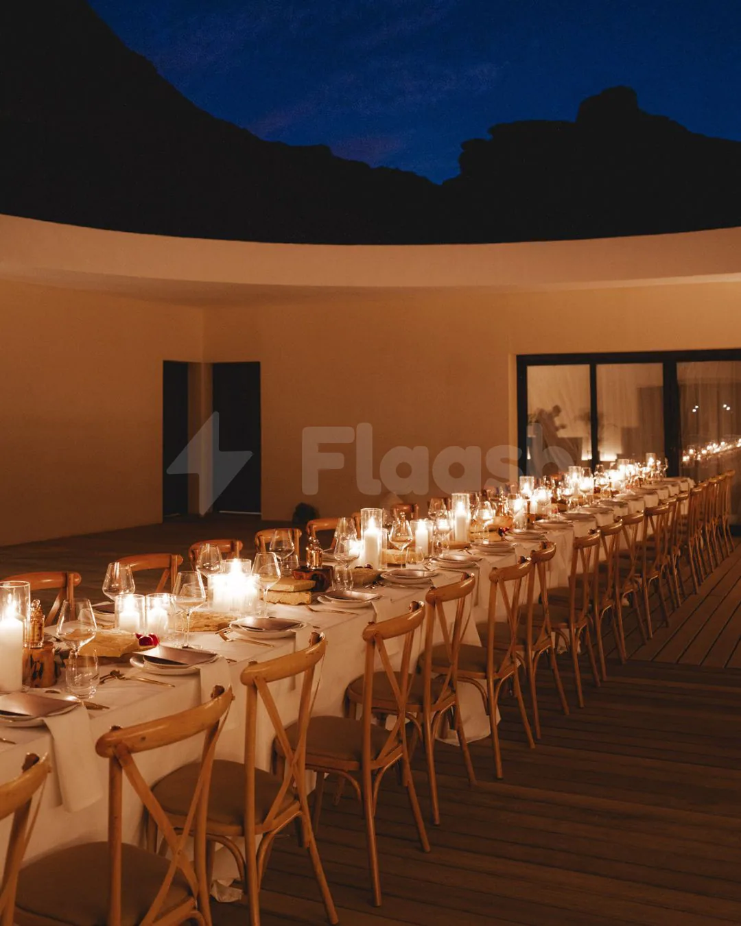 Long dining table at Tama At Habitas AlUla in Al Ula with candlelit ambiance and mountain silhouette backdrop