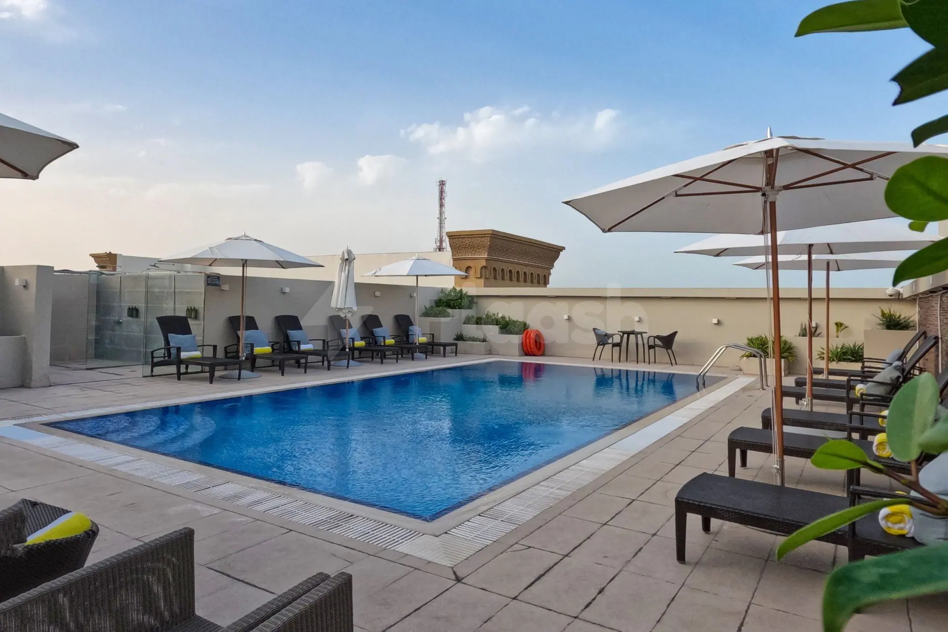 Rooftop swimming pool at Time Rako Hotel Qatar in Doha with blue water, tiled deck, white umbrellas