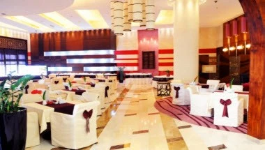 Banquet hall at Grand Regal Hotel, Doha, with white chairs and red sashes under tiered lighting