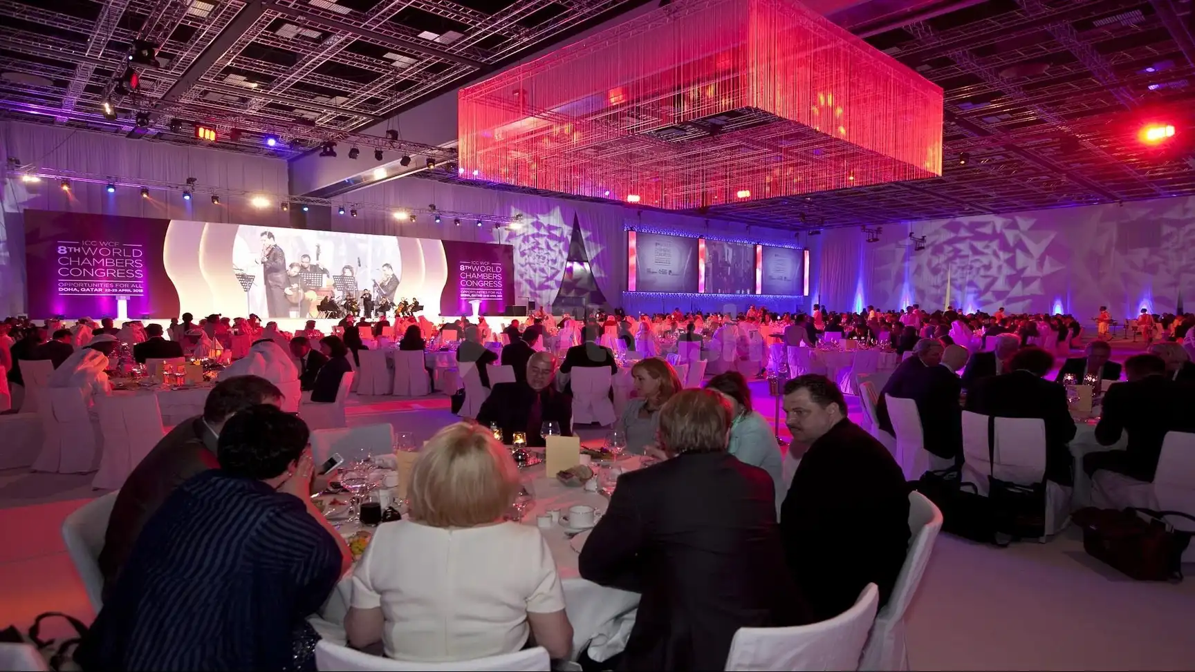 A vibrant conference space at Qatar National Convention Centre, Doha, featuring a large illuminated cube installation