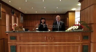Reception desk at Al-Muntazah Plaza Hotel, Doha, with wooden paneling and floral arrangement