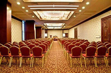 Conference hall at Swiss-Belhotel Doha, Doha, with rows of red chairs and ornate ceiling lights