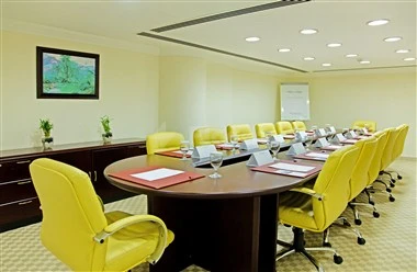 Conference room at Swiss-Belhotel Doha, Doha, featuring yellow chairs and a large oval table with documents