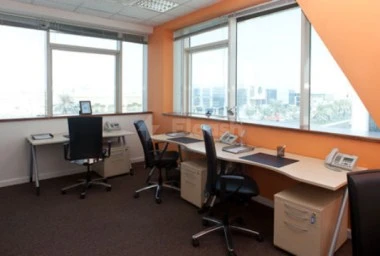 Workspace at Regus - Doha Airport, Doha, with orange walls and large windows overlooking cityscape