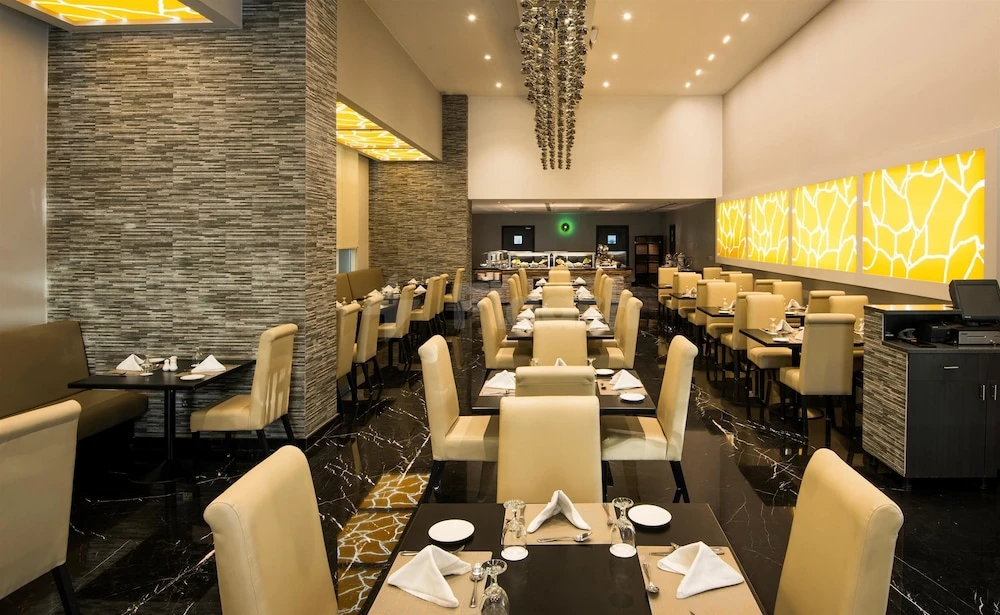 Dining room at Best Western Plus Doha, Doha, featuring marble floors and a modern chandelier above beige chairs