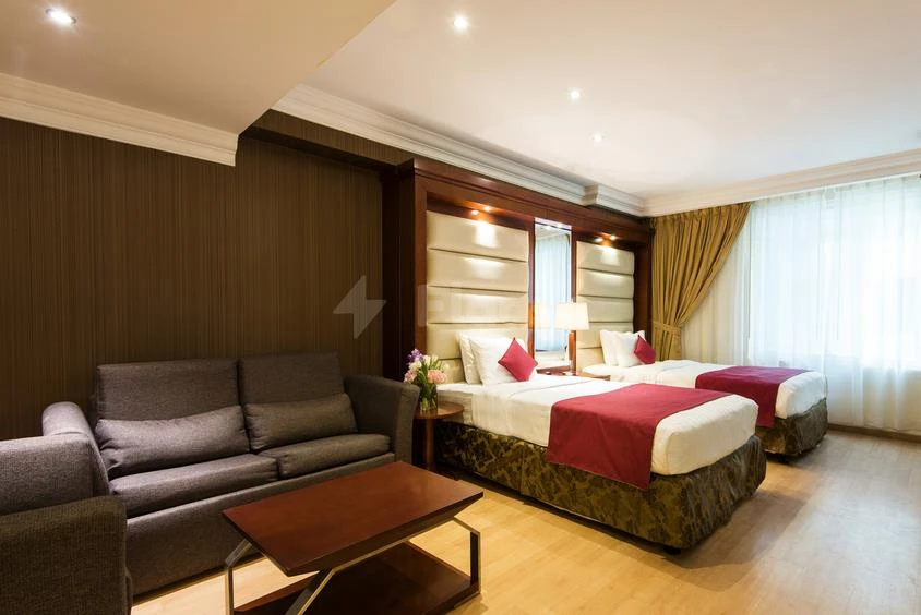 Guest room at Best Western Plus Doha, Doha, featuring twin beds with red accents and a gray sofa