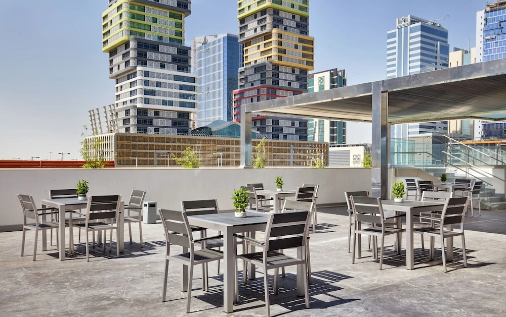 Rooftop terrace at Staybridge Suites Doha Lusail, Lusail, with modern tables and potted plants against city towers