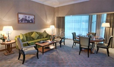 Lounge at Retaj Royale Doha, Doha, with green sofa and round dining table near large windows