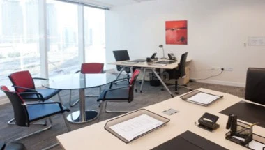 Modern office space at Regusschläger Doha West Bay, featuring glass walls looking out over city skyline, sleek