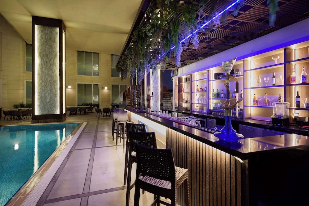 Poolside bar at DoubleTree by Hilton Doha - Al Sadd, Doha, with blue neon lighting and hanging greenery