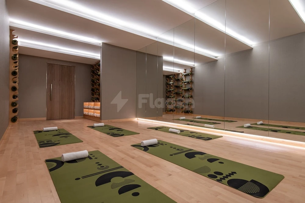 Yoga studio at Abesq Doha Hotel & Residences, Doha, with mirrored walls and patterned mats on wooden floors