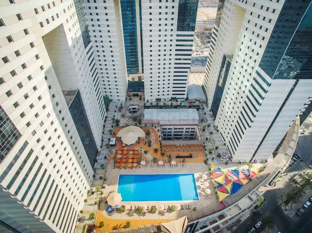 Pool deck at Ezdan Hotel & Suites, Doha, featuring vibrant umbrellas and surrounding high-rise towers
