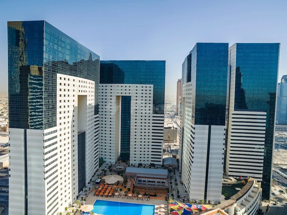 Skybridge connecting towers at Ezdan Hotel & Suites, Doha, with reflective glass façades and rooftop pool below