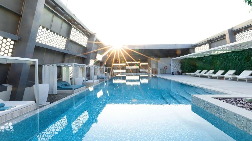 Outdoor pool at Steigenberger Hotel Doha, with geometric lattice walls and sunbeds under bright sunlight