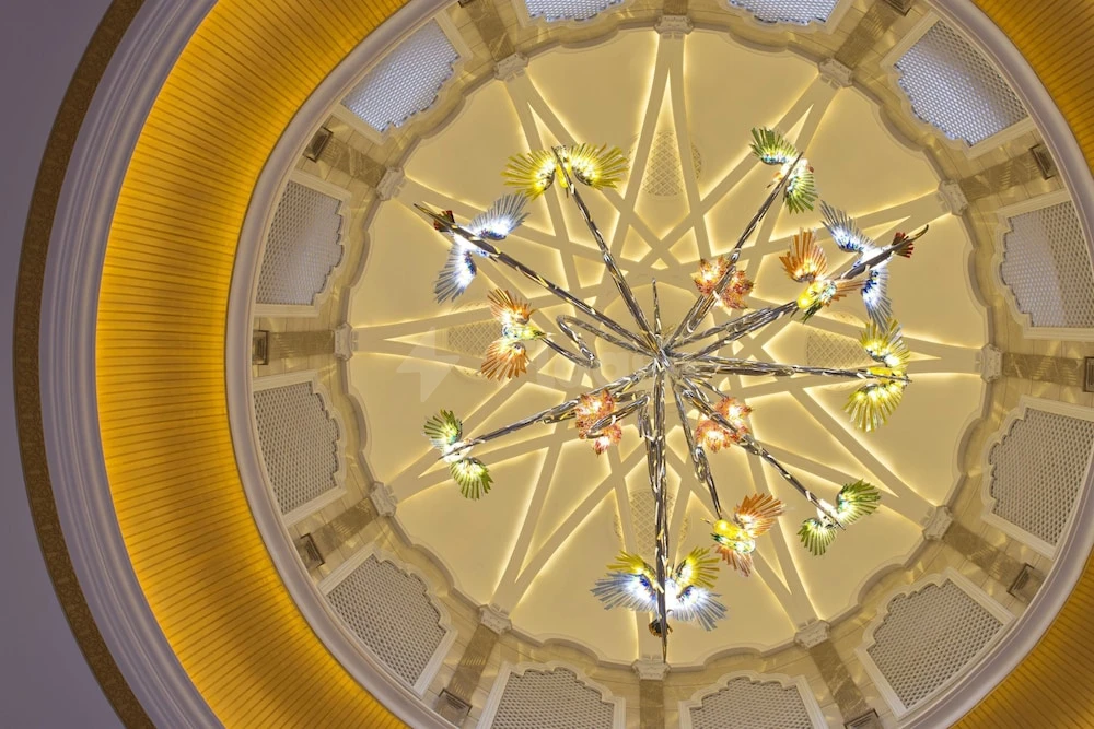Grand chandelier at Marsa Malaz Kempinski, Doha, featuring ornate bird motifs and golden accents under a domed ceiling