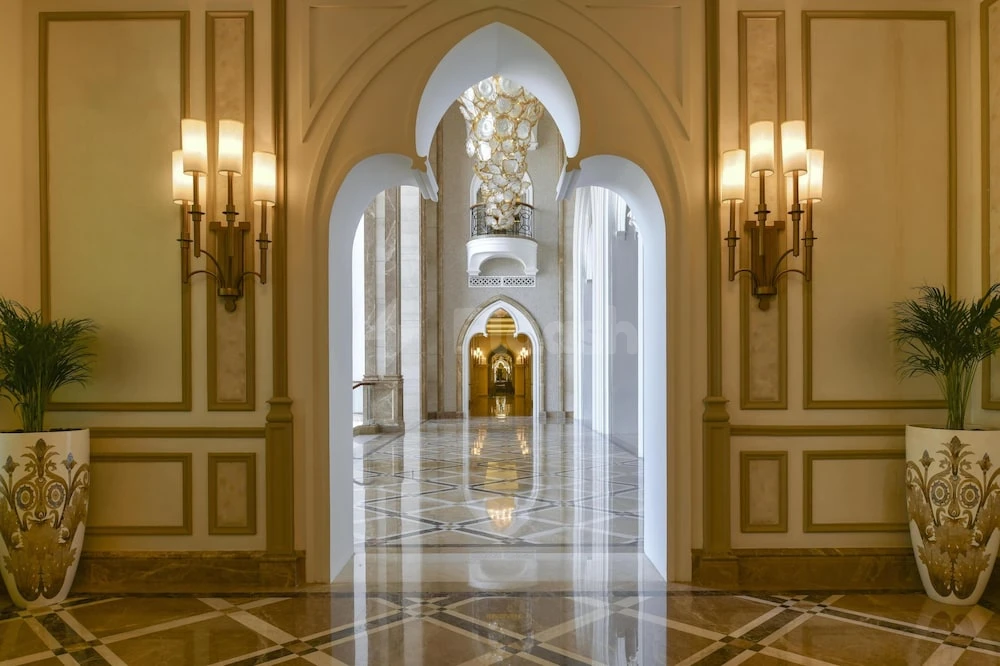 Grand entrance hall at Marsa Malaz Kempinski, Doha, featuring arched doorways and ornate wall sconces with gold accents
