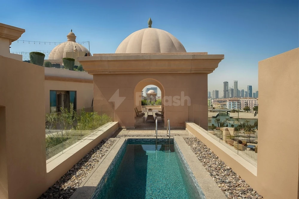 Rooftop pool at Marsa Malaz Kempinski, Doha, framed by domed archway and city skyline view