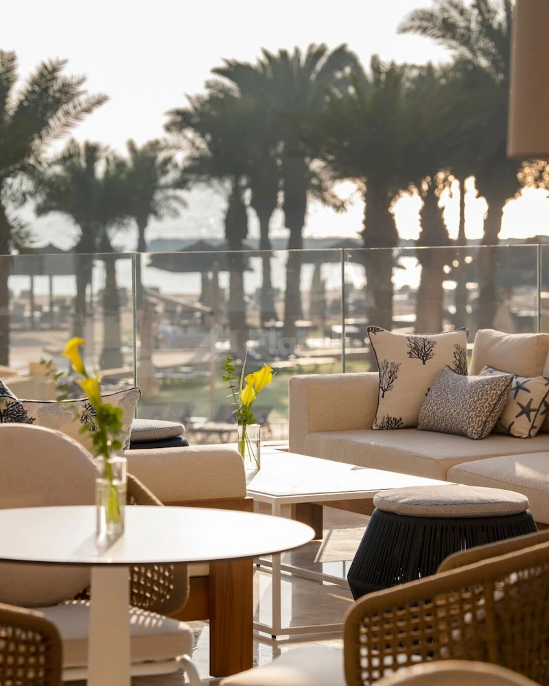 Outdoor lounge at Intercontinental Doha Beach & Spa, Qatar, featuring rattan chairs and sea views through glass railings