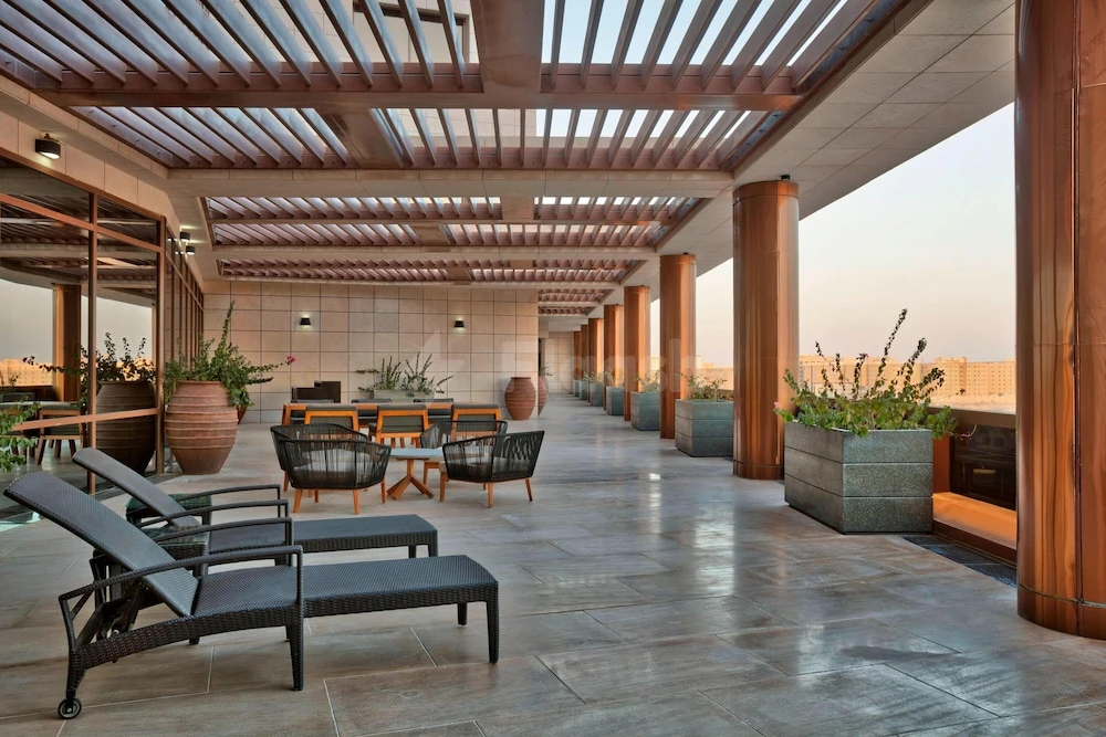 Rooftop terrace at The Westin Doha Hotel & Spa, Doha, with lounge chairs and large planters under wooden pergolas