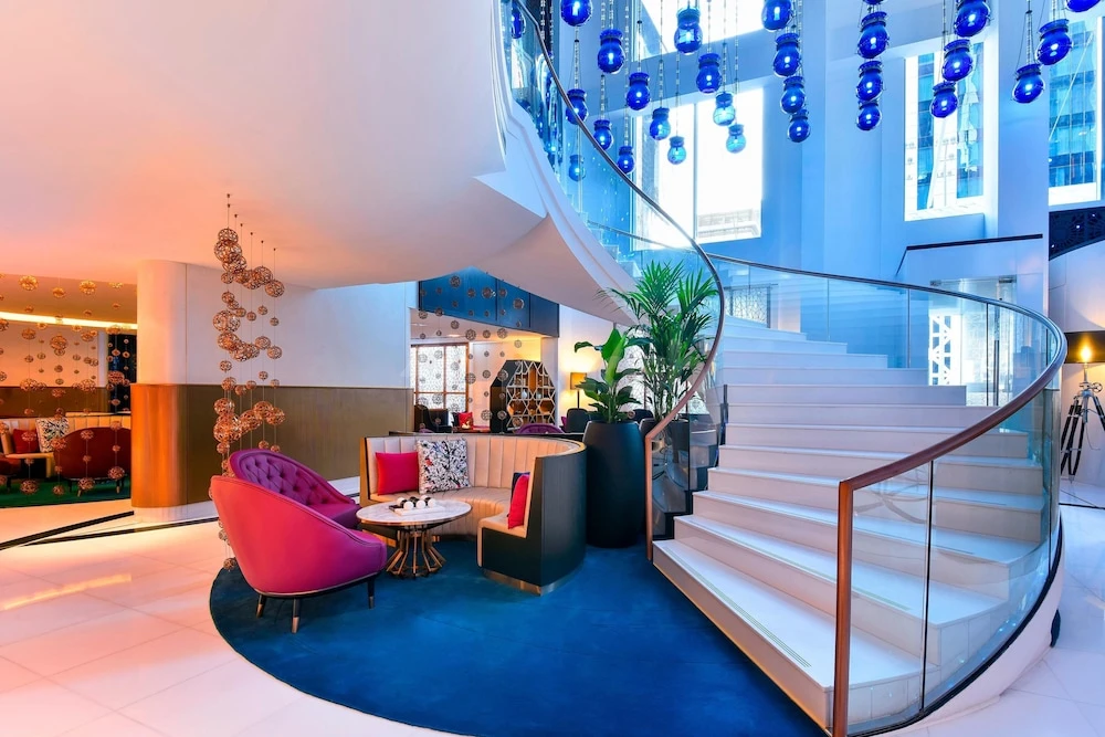 Lobby at W Doha, Doha, featuring a spiral staircase with blue glass orbs and vibrant pink seating