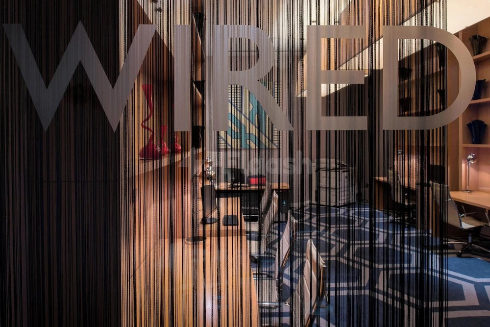 Wired lounge at W Doha, Doha, with black string curtain partition and geometric blue carpeting