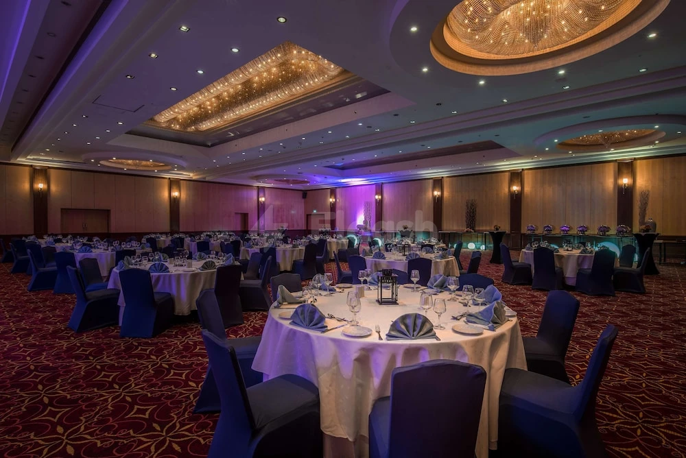 Banquet hall at Radisson Blu Hotel, Doha, with round tables draped in white linens and blue chair covers