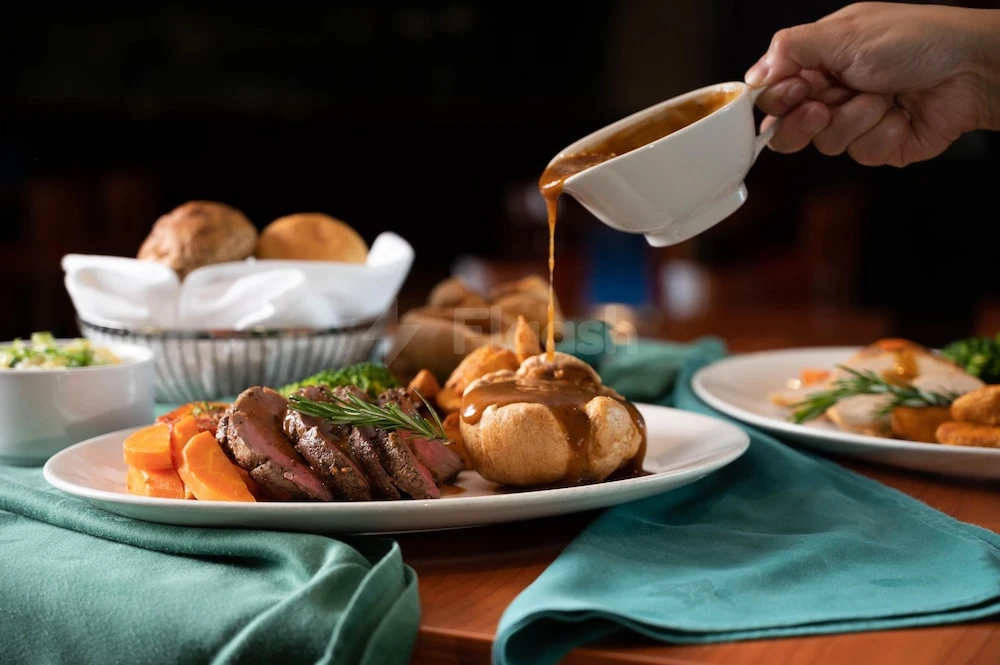Dinner service at Radisson Blu Hotel, Doha, with rich gravy being poured over roasted meat and vegetables