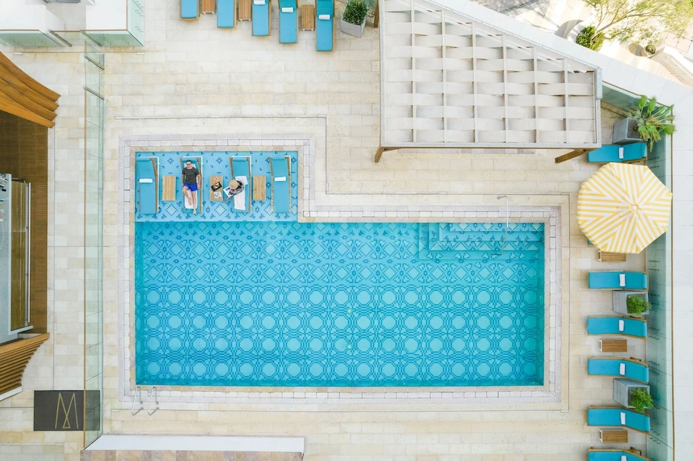 Pool deck at Alwadi Hotel Doha MGallery By AccorHotels, Doha, with turquoise tiled pool and blue lounge chairs