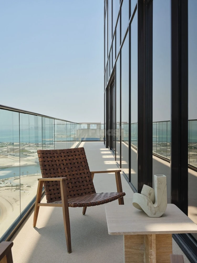 Rooftop terrace at The OQ Hotel, Lusail, featuring woven chair and marble side table with sea view