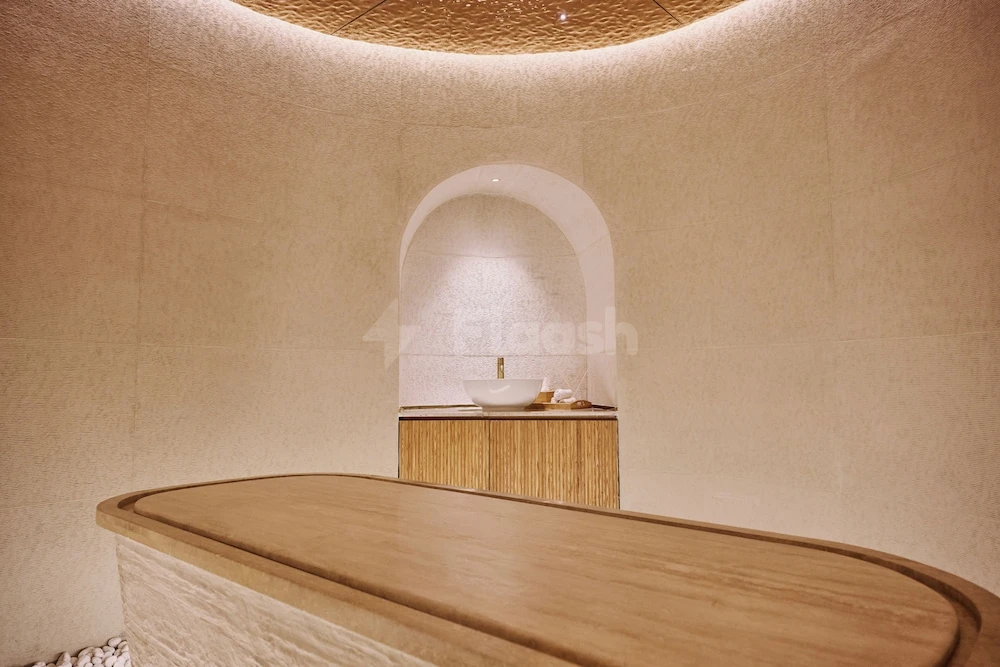 Sensory spa room at The OQ Hotel, Lusail, featuring a wooden lounge bed and arched stone washbasin niche