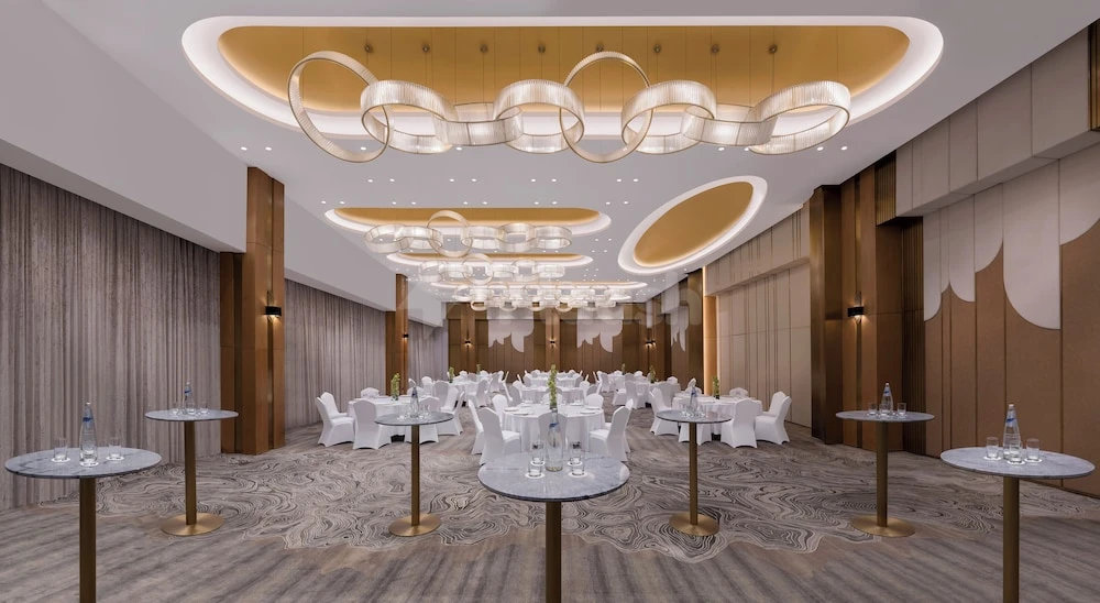 Banquet hall at Velero Hotel Doha Lusail, Lusail, with circular chandeliers and white tablecloths