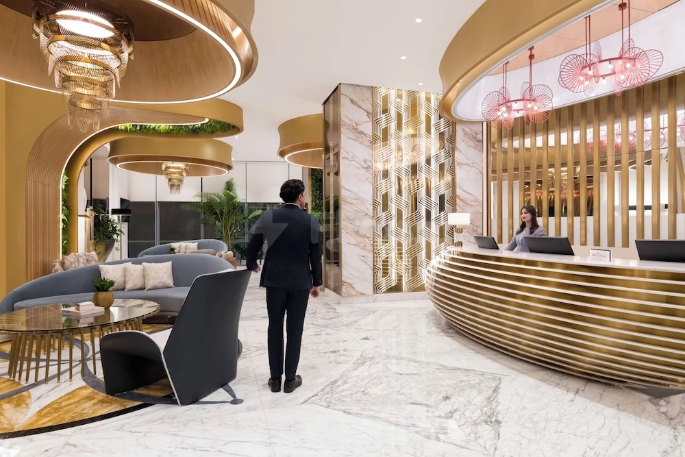 Lobby at Velero Hotel Doha Lusail, Lusail, with golden curved reception desk and marble flooring