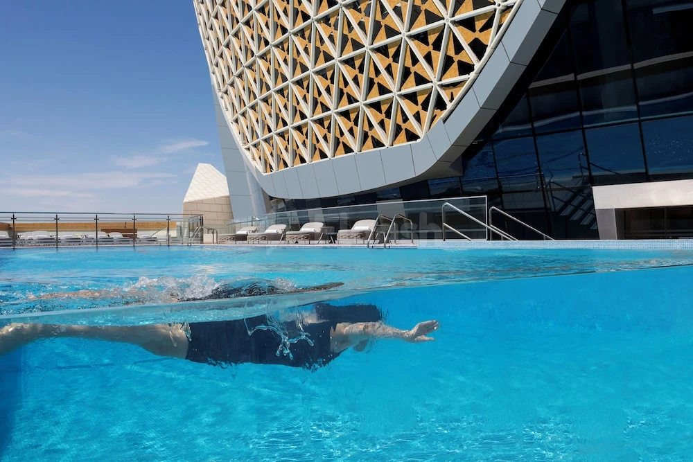 Rooftop infinity pool at Velero Hotel Doha Lusail, Lusail, with geometric facade and clear blue water