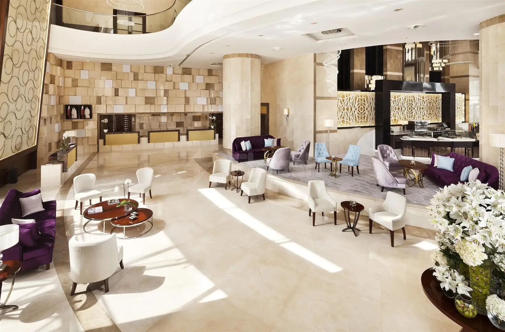 Lounge area at Melia Doha, Doha, with purple sofas and white armchairs arranged around circular tables