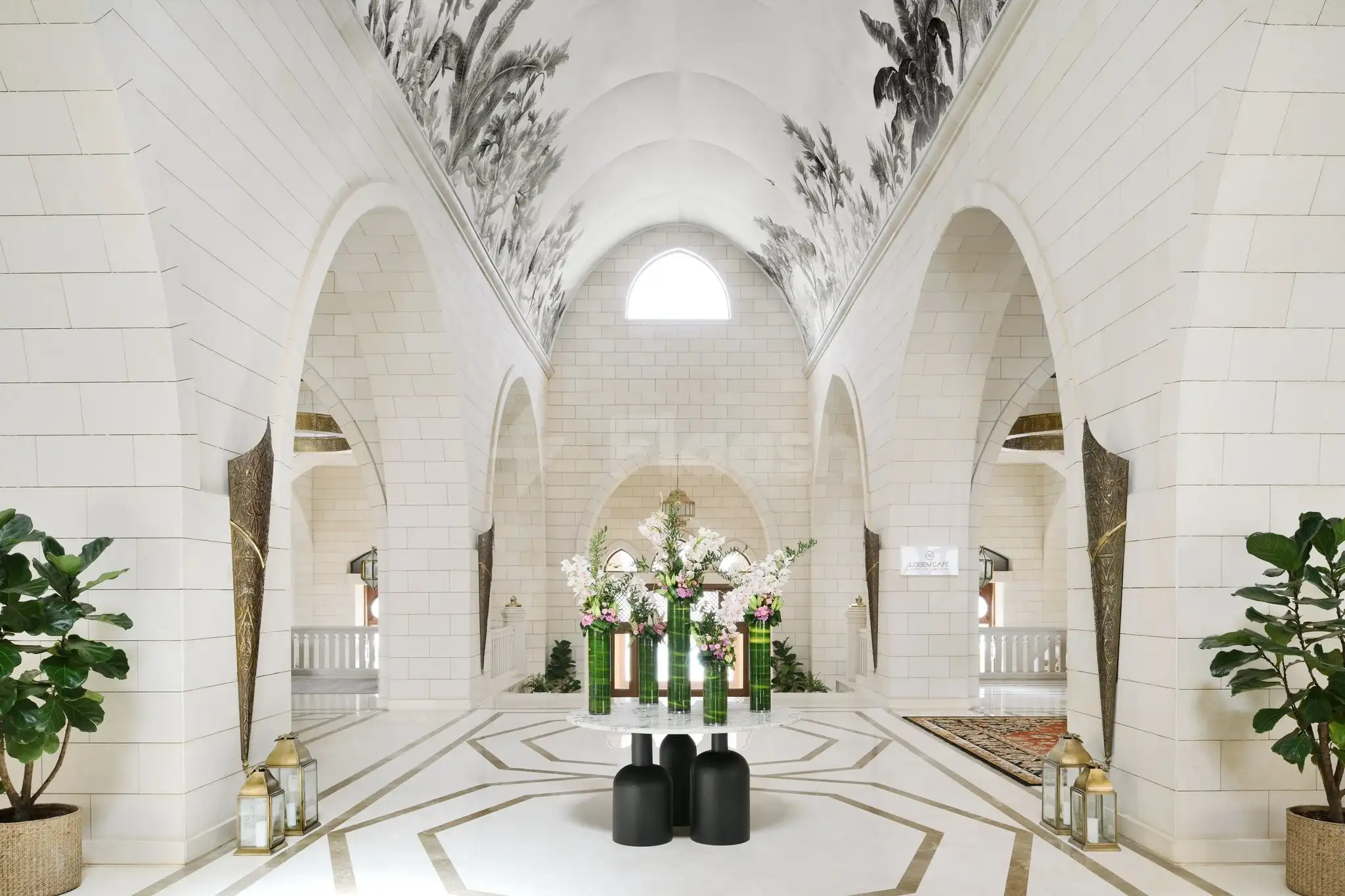 White arched corridor at InterContinental Durrat Al Riyadh Resort & Spa, Riyad, with floral arrangements on green vases