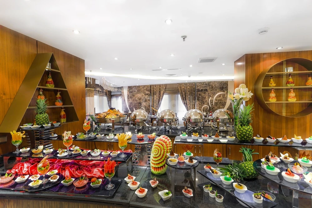 Buffet hall at Elaf Kinda Hotel, Mecca, featuring carved watermelons and pineapple centerpieces on dark marble counters