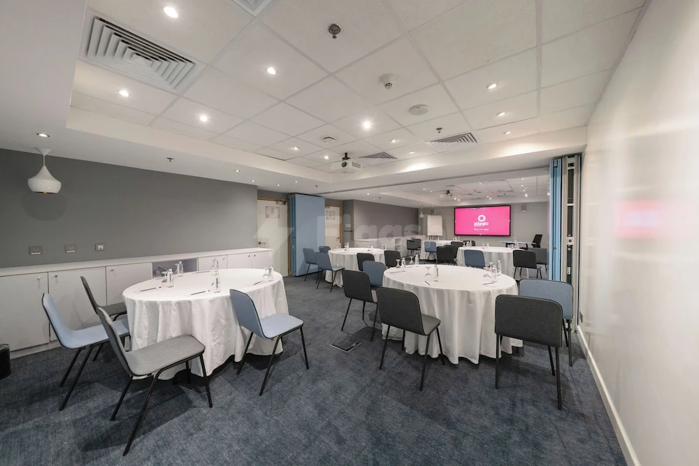 Conference space at ibis Jeddah City Center, Jeddah, with round tables covered in white linens and blue chairs