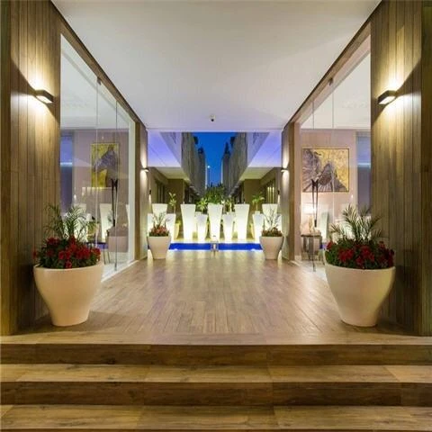 Lobby at Vivienda Residence, Riyadh, featuring wooden floors, potted plants, and a blue-lit water feature