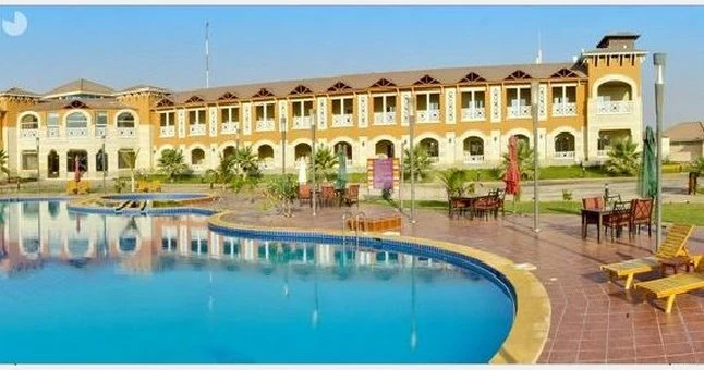 Poolside lounge area at Bouded Half Moon Resort, Khobar, featuring sun loungers and a curved swimming pool reflecting