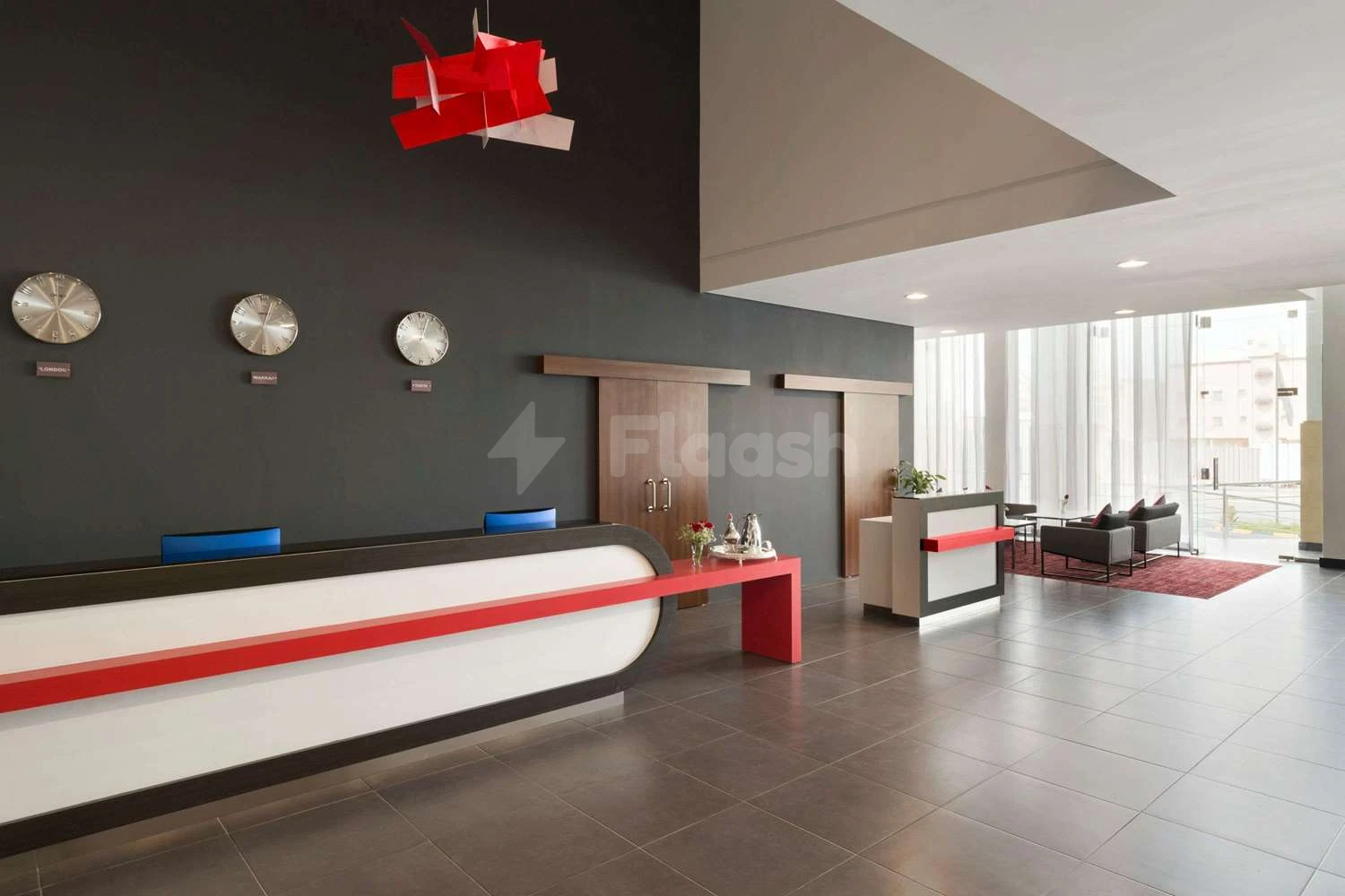 Modern lobby at Ramada Encore by Wyndham Al Khobar Olaya, Al Khobar, with red accent lighting above reception