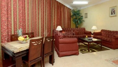 Living room at Boudl Al-Corniche, Dammam, with red patterned curtains and matching sofa set