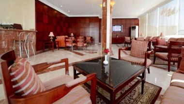 Lounge area at Boudl Al-Corniche, Dammam, featuring wooden furniture and a central coffee table with red accents