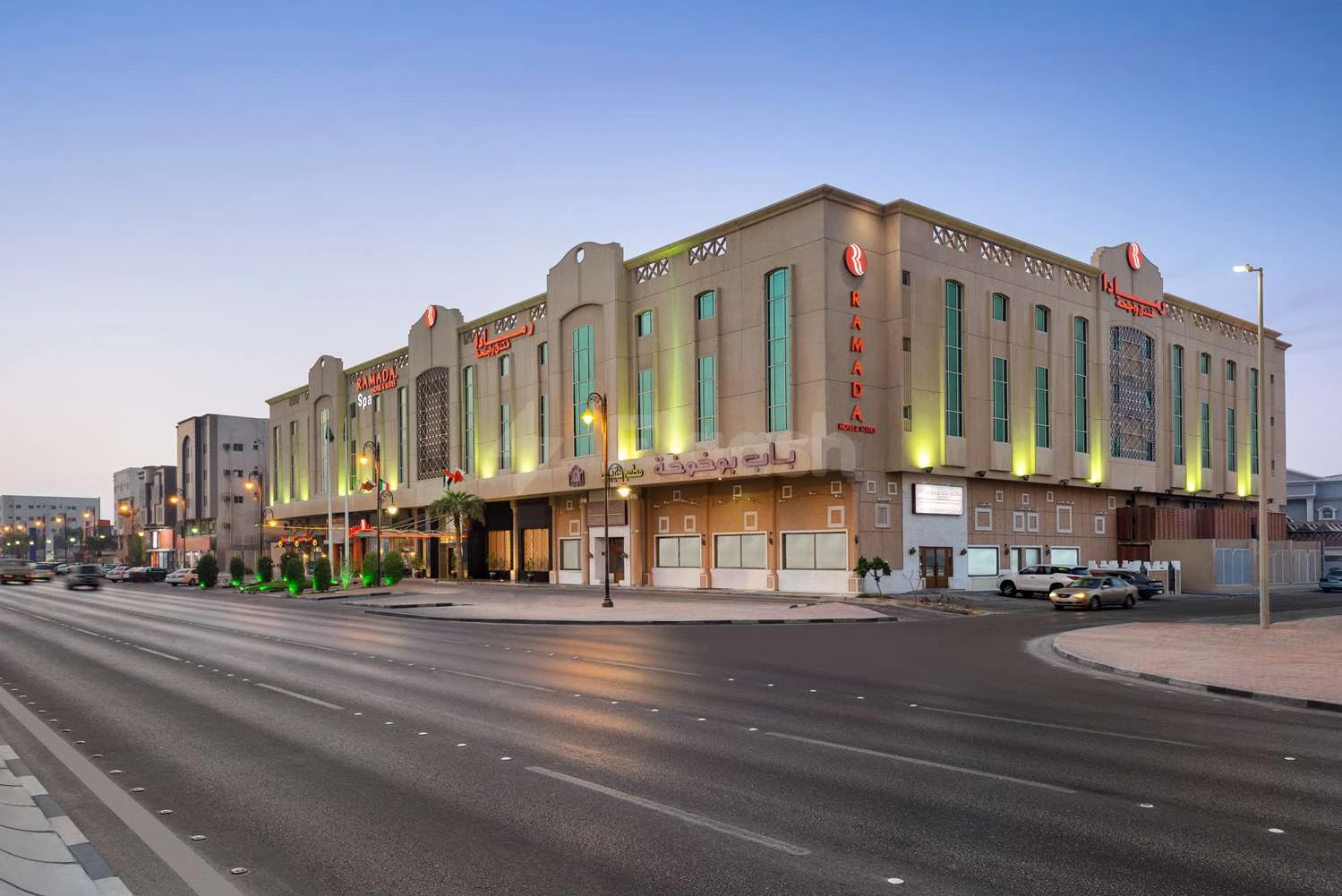 The hotel's facade features illuminated signage and green accents along its exterior walls