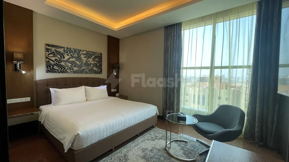 Guest room at M Hotel Makkah By Millennium, Mecca, featuring a king-sized bed and large window with city