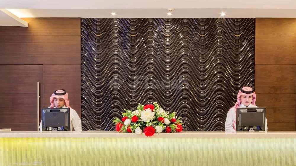 Reception area at M Hotel Makkah by Millennium, Mecca, featuring wavy metallic wall paneling and floral arrangement