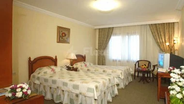 Bedrooms at Al Azhar Hotel Jeddah, with floral bedding and curtains framing a window view