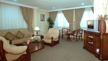 Cozy lounge at Al Azhar Hotel Jeddah, featuring wooden furniture and beige drapes with a vintage TV console
